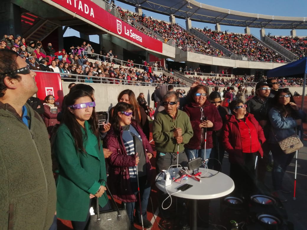 Grupo de personas experimentando el eclipse total de Sol del 2 de julio de 2019 con dispositivos LightSound en evento en el estadio La Portada en la Serena, Chile. Créditos: LightSound.